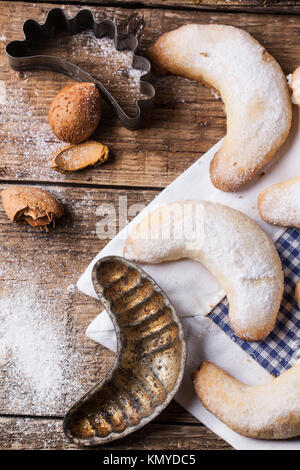 Vista superiore SU dello zucchero in casa cookie crescent servita con vintage cookie cutters, mandorle e tessuto sopra il vecchio tavolo in legno Foto Stock