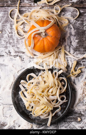 Vista dall'alto su materie pasta fatta in casa con la zucca e farina sopra il vecchio tavolo in legno Foto Stock