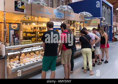 I turisti acquistano i formaggi locali nel mercato coperto di Colmar Foto Stock