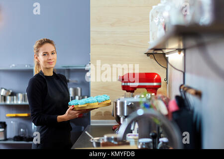 Pasticcere donna tenendo un vassoio di tortine. Foto Stock