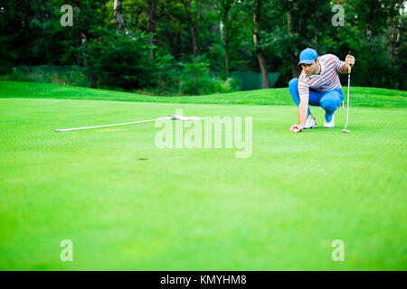 Giocatore di Golf palla di marcatura sul putting green Foto Stock