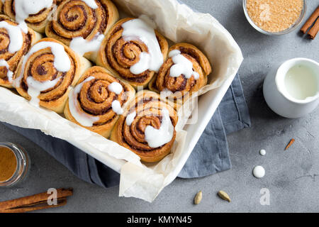 Panini alla cannella o cinnabons con salsa di panna fatti in casa preparazione ricetta dolce dessert tradizionali panini pasta alimentare. Cibo per ingridients cannella ro Foto Stock