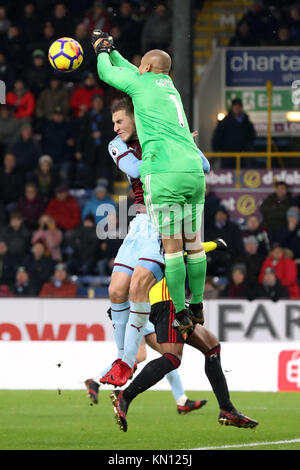 Watford portiere Heurelho Gomes punzoni la sfera chiara sotto pressione da Burnley's Chris Wood durante il match di Premier League a Turf Moor, Burnley. Foto Stock