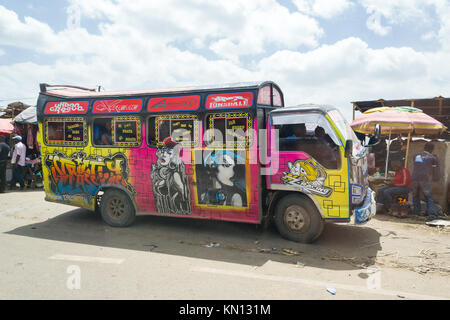 Un bus luminosamente decorate con arte arrestata dal lato della strada accanto ad una piccola platea, Nairobi, Kenya, Africa orientale Foto Stock