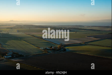 Byres Hill, East Lothian, Scozia, Regno Unito, 10 dicembre 2017. Cancellare freddo giorno di East Lothian campagna con un luminoso cielo blu. Vista nebbiosa guardando verso l'Arthurs Seat di Edimburgo a distanza Foto Stock