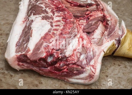 Sul tavolo giaceva un gran pezzo di carne di maiale per ulteriore elaborazione. Foto Stock