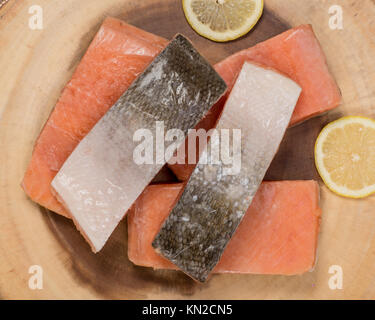 Il salmone congelato i filetti di pesce con fette di limone isolato sul pannello di legno. Foto Stock