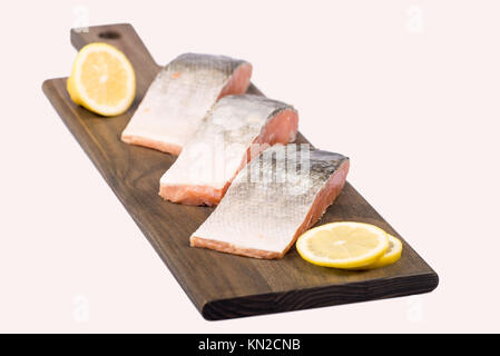Il salmone congelato i filetti di pesce con fette di limone isolato sul pannello di legno. Foto Stock