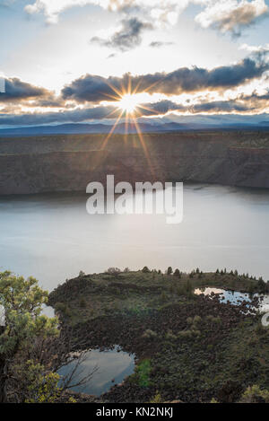 Nuvole parte per far fare al tramonto un sun star sopra l'acqua del cove Palisades vicino a Culver, Oregon Foto Stock