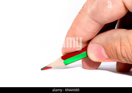 Un uomo tenere in mano una matita verde sul bianco scrivania, tavolo bordo bianco isolato in studio. Due-tono di matita e di colore verde e rosso. Matite con doppio co Foto Stock