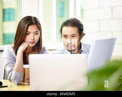 Due asian corporate executives imprenditore e imprenditrice lavorando insieme in office analizzando un report utilizzando il computer portatile. Foto Stock