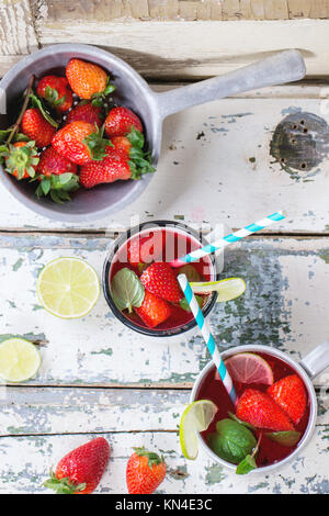 Vintage tazze in metallo con cocktail retrò tubi fatti in casa con fragole limonata, servita con fragole fresche, menta e calce su un vecchio legno bianco ta Foto Stock