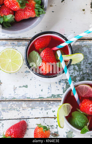 Vintage tazze in metallo con cocktail retrò tubi fatti in casa con fragole limonata, servita con fragole fresche, menta e calce su un vecchio legno bianco ta Foto Stock