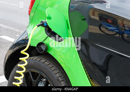 Close up di auto elettrica essendo in carica Foto Stock