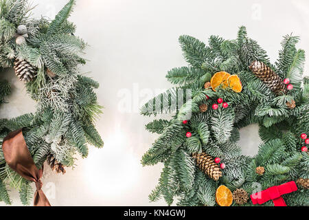 Interior design, natale, concetto d'inverno. rami fuzzy di conifera albero intessute in ordinate cerchio con nastri e prua con bacche rosse e pigne nelle quali, e persino di frutta secca Foto Stock