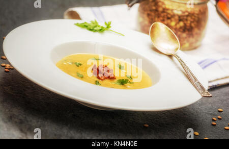 Rosso, zuppa di lenticchie con salsicce alla griglia in piastra bianca sulla pietra scura Foto Stock