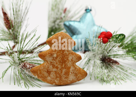 Lo zenzero cookie nella forma di albero di Natale con blue ninnolo e pino coperto di neve Foto Stock