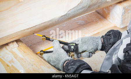 Close-up di un uomo un builder e un taglialegna disegna un tronco di legno con una bussola in modo che possa poi essere sawed con una sega circolare per la costruzione di una casa in t Foto Stock