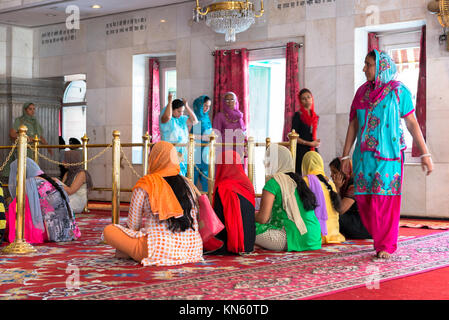 NEW DELHI, India - 18 Marzo 2016: immagine orizzontale delle donne indiane di religione Sikh seduto sul pavimento all'interno Sisganj Gurudwara Sahib, situato in Foto Stock