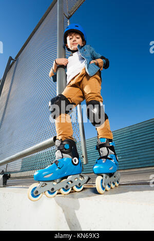 Ritratto a figura intera di preteen boy, inline skater in abbigliamento protettivo, ponendo a skate park e guardando la fotocamera Foto Stock