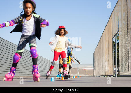 Ritratto di ragazze africane, felice inline skater, apprendimento di slalom in avanti a skate park a giornata di sole Foto Stock