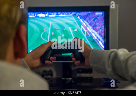 Un bambino gioca una partita di calcio sulla sua console playstation Foto Stock