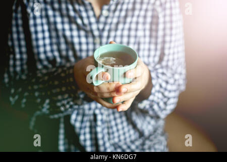 Le mani delle donne in possesso di una tazza di tè, tonificante Foto Stock