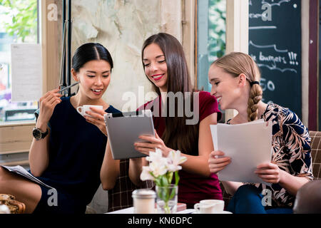 Giovani donne tenendo i file in un coffee shop Foto Stock