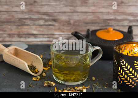 Calda tè verde in tazza di composizione con candela e teiera Foto Stock