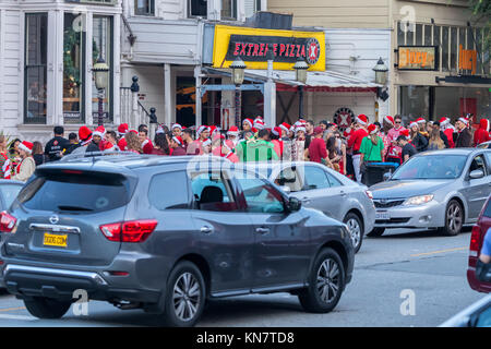 Giovani frequentatori di partito, vestiti da Babbo Natale , in attesa in fila per entrare in un bar per la Santa con la celebrazione in San Francisco, California, Stati Uniti. Foto Stock