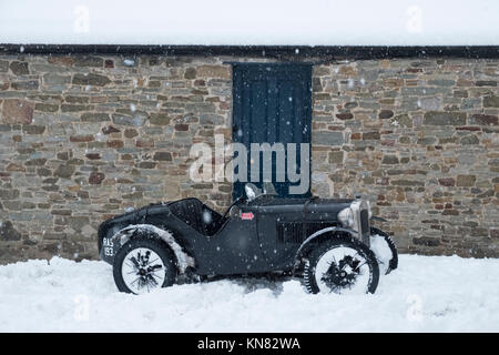 Presteigne, Powys, Wales, Regno Unito. Il 10 dicembre 2017. Una forte nevicata copre gran parte del Galles tra cui questa piccola cittadina gallese. Un vecchio vintage Austin auto sportiva è catturato nella neve. Alex credito Ramsay / Alamy Live News Foto Stock