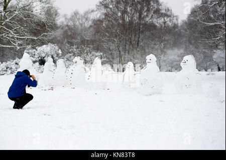 Sutton Coldfield, Regno Unito. 19 Settembre 2017. Un uomo che fotografa una fila di 8 snowmen a Sutton Park, Sutton Coldfield. Vista generale della forte caduta di neve a Sutton Coldfield, West Midlands, Regno Unito. Un avvertimento ambrato di neve pesante, che inizia alle 4 di domenica 10 dicembre 2017, è stato emesso per le West Midlands. Credit: NexusPix/Alamy Live News Foto Stock