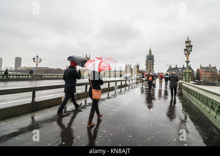 Londra, Regno Unito. Undicesimo Dec, 2017. Londra di Mattina pendolari battaglia il freddo Pioggia gelata, alta venti pioggia e grandine sul Westminster Bridge in ciò che è noto come Black Ice lunedì un giorno dopo la prima nevicata nella capitale. Il Met Office ha emesso gli avvisi di ambra per significative nevicate in molte parti del Regno Unito con il rischio di gravi perturbazioni al credito di viaggio: amer ghazzal/Alamy Live News Foto Stock