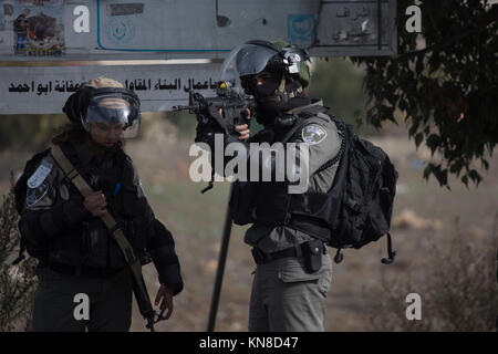 Un soldato israeliano si propone la sua arma durante gli scontri con i dimostranti palestinesi di Beit El, al di fuori di Ramallah, West Bank, 11 dicembre 2017. Nuove proteste si sono scatenati fino in risposta al Presidente americano Donald Trump per la decisione di riconoscere Gerusalemme come capitale di Israele. Foto: Oren Ziv/dpa Foto Stock