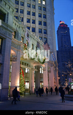 Chicago, Stati Uniti d'America. Decimo Dec, 2017. Gli acquirenti di vacanza su Michigan Avenue's 'Magnificent Mile' a piedi passato le luci di Natale sul Wrigley Building su un vivace serata in Chicago. Credito: D Valutazione Smith/Alamy Live News Foto Stock