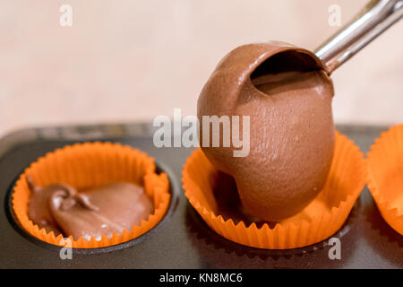 Versando Cake Mix in lievito muffin vassoio Foto Stock