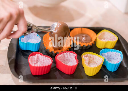 Versando Cake Mix in lievito muffin vassoio Foto Stock