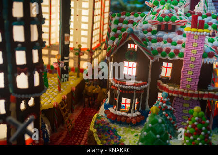 Close-up dettagli di panpepato città di case, uffici, albero di Natale e una carrozza a cavallo su strada con luci interne shining Foto Stock