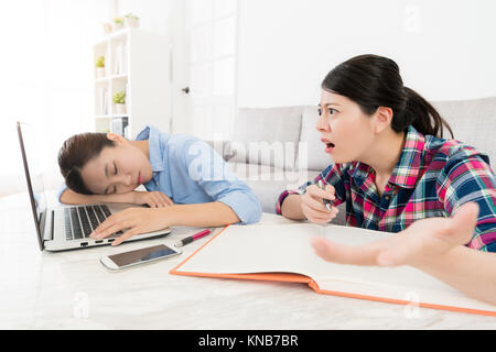 Infelice bellezza ragazza trovando il suo compagno dorme sentirsi confuso quando essi studiano nel soggiorno per preparare la scuola esame. Foto Stock