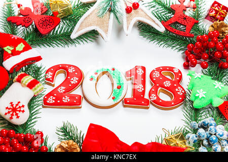 Ghirlanda di Natale con decorazioni con pan di zenzero 2018, ramo di albero di Natale su sfondo bianco. Un simbolo di inverno e le vacanze di capodanno. Foto Stock