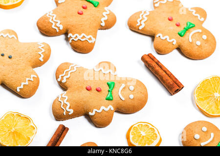 Natale gingerbread uomini con limone e bastoncini di cannella su sfondo bianco. Un simbolo di inverno e le vacanze di capodanno. Foto Stock