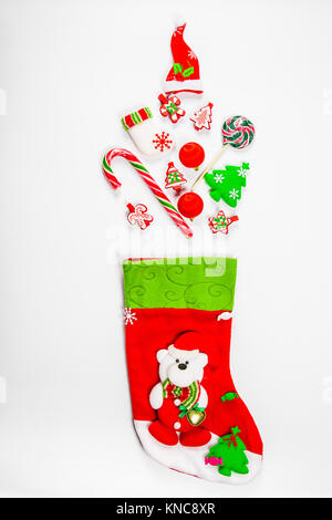 Sfondo di natale con un calzino da cui doni sparsi, candy, Nuovo Anno decorazioni giocattoli su uno sfondo bianco. Il concetto di pubblicità, shopp Foto Stock