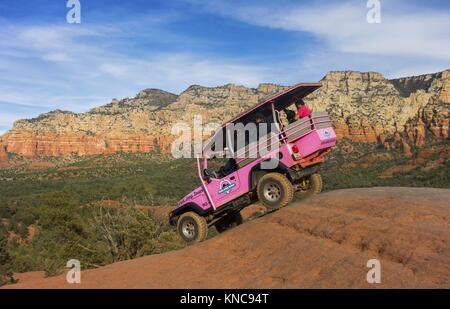 Jeep rosa fuori strada veicolo terreno ad alta distanza in tour rotto Arrow Slick Rock Desert Landscape con i turisti a bordo vicino Sedona Arizona Foto Stock