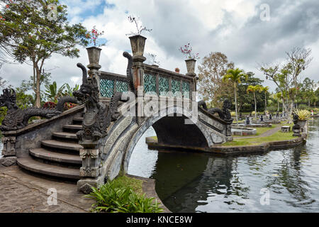 Con il ponte di pietra scolpita dragons nella Tirta Gangga acqua palace, un ex palazzo reale. Karangasem regency, Bali, Indonesia. Foto Stock