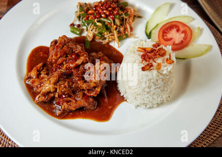 La carne di maiale in dolce la salsa di soia con riso e verdure servita in un locale il warung (piccolo ristorante). Bali, Indonesia. Foto Stock