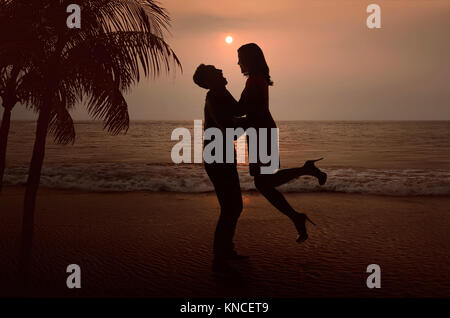 Silhouette di coppia asiatica in amore sulla spiaggia al tramonto Foto Stock