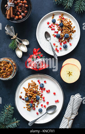 In casa granola, mirtilli i semi di melograno e yogurt. Tabella vista dall'alto di una sana colazione di Natale. Dieta, mangiare sano concetto Foto Stock