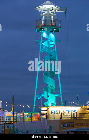 Il Brighton Zip illuminato in blu al tramonto con il fish & chips stallo a Brighton in Dicembre Foto Stock