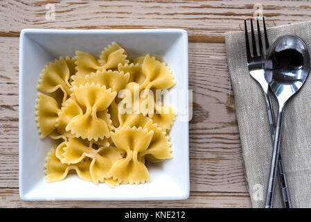 Ciotola farfalle cucinate la pasta con una forchetta e cucchiaio e tovagliolo, salvietta. Foto Stock