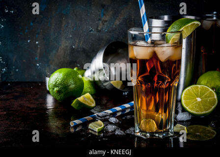 Cuba Libre, long island o tè freddo cocktail con alcool, cola di lime e il ghiaccio, due, Vetro scuro dello sfondo spazio copia Foto Stock